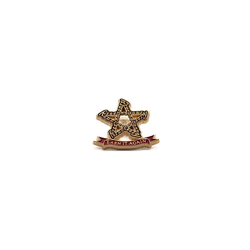 Star-shaped lapel pin outlined with text reading "Freemasonry," with red banner below it reading "Earn It Again."