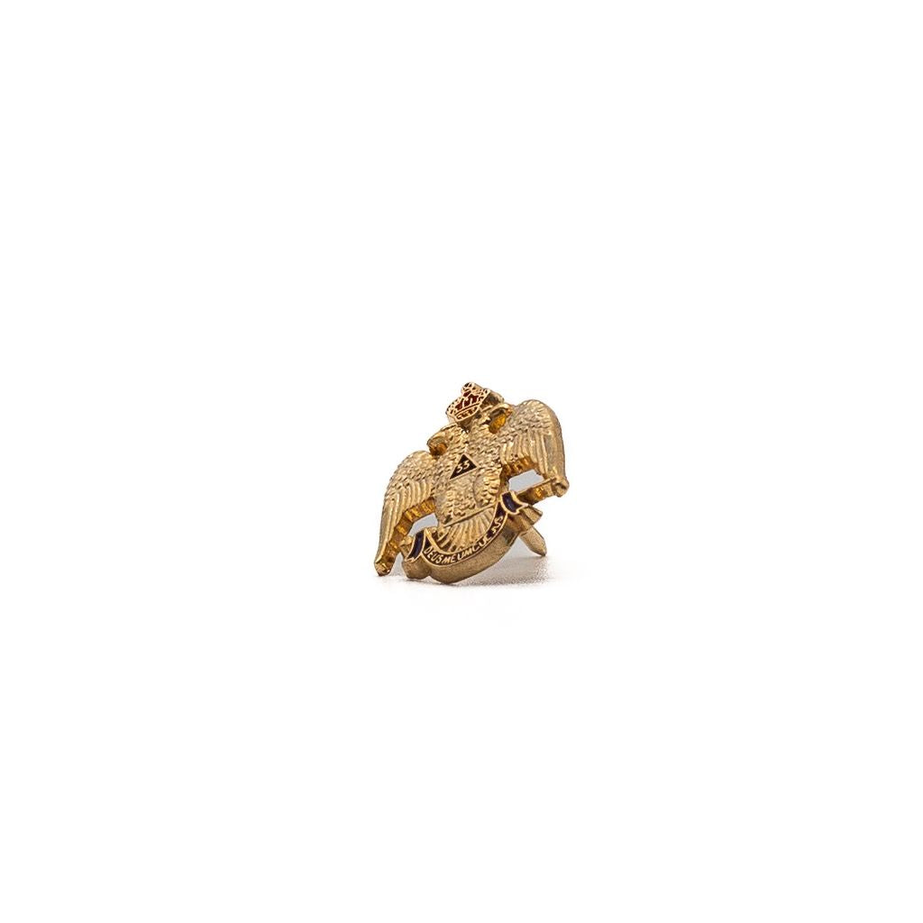 Closeup of goldtoned pin with two headed eagle. 