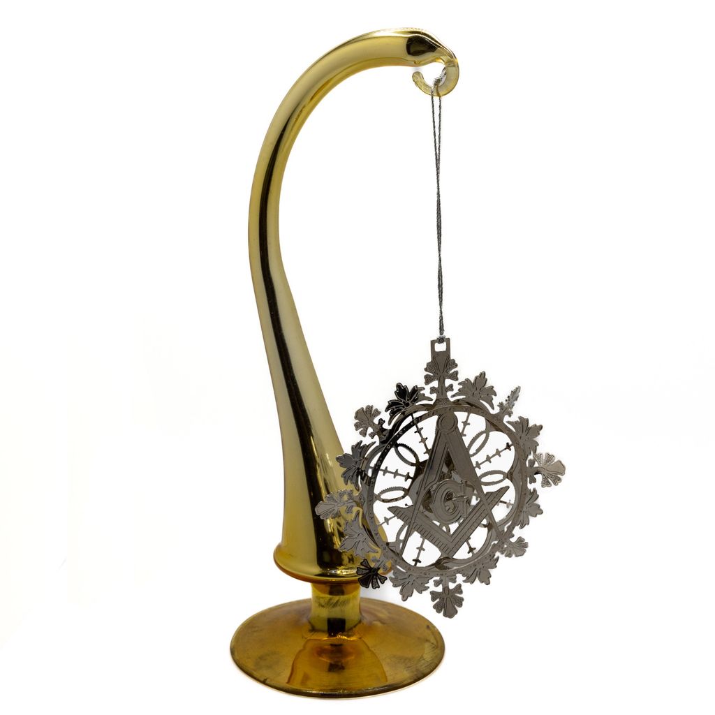 Decorative ornament in silver with geometric and Square and Compass design hanging from hook on a white background