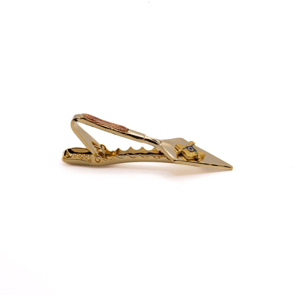 Gold trowel-shaped tie clip with a Square and Compass on a white background