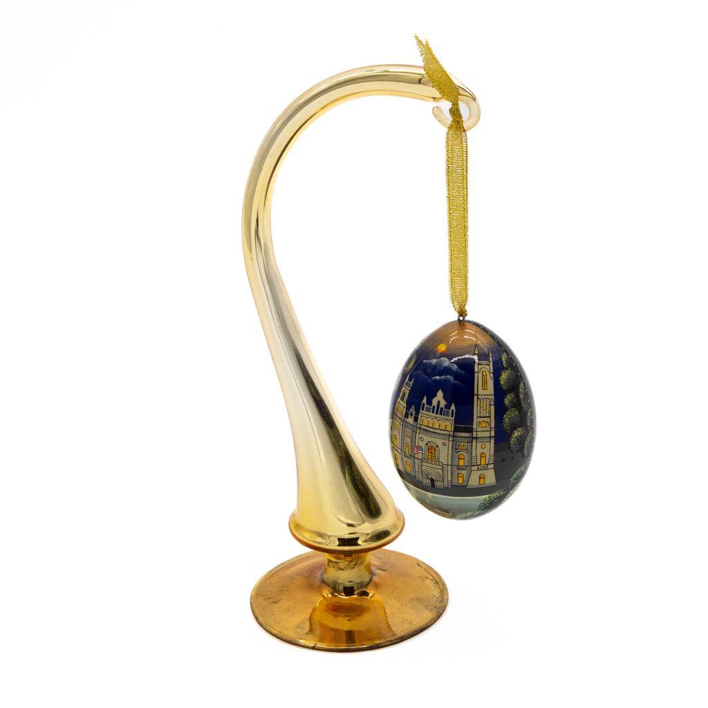 Decorative detailed egg-shaped ornament hanging on hook on a white background