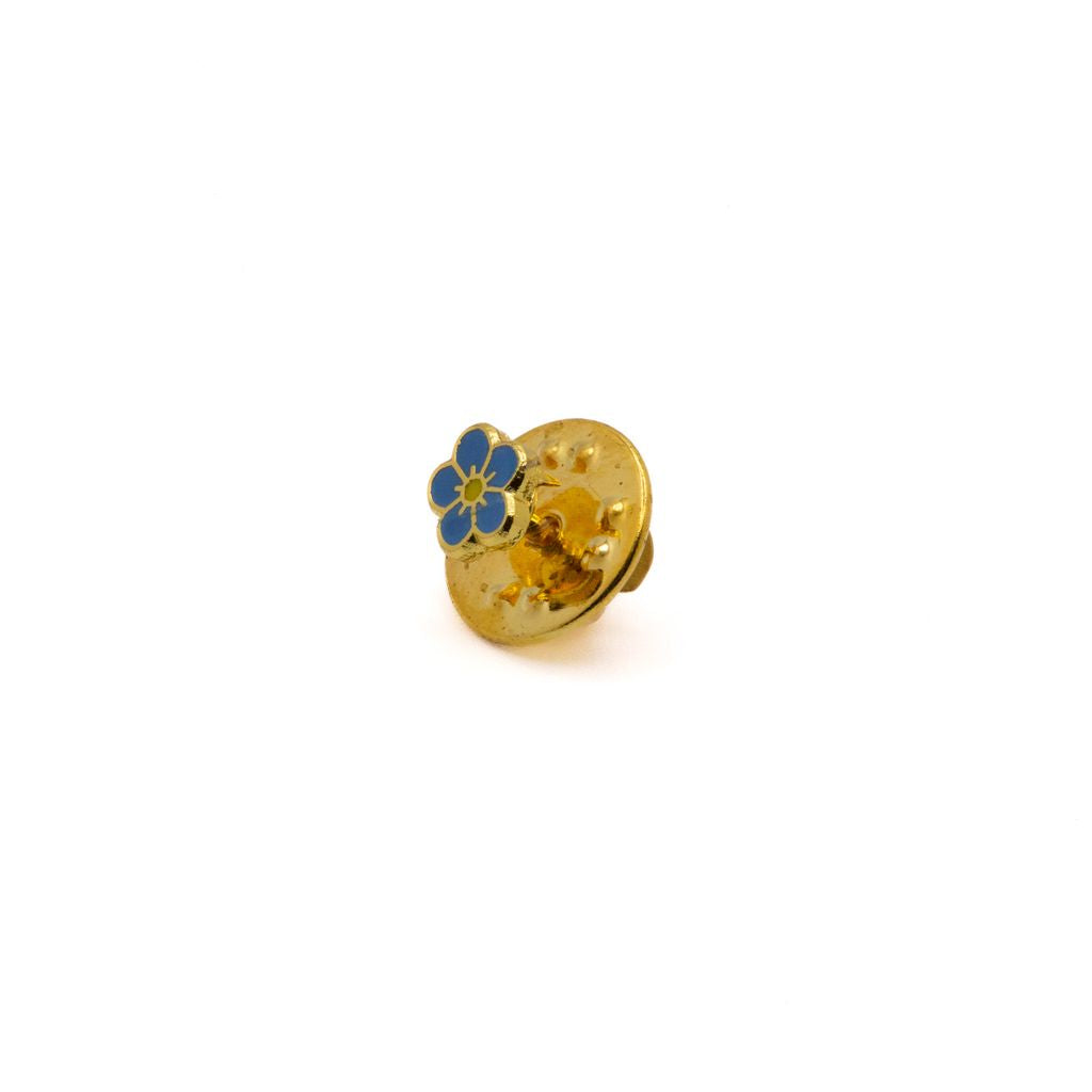 Gold lapel pin with a blue flower design on a white background