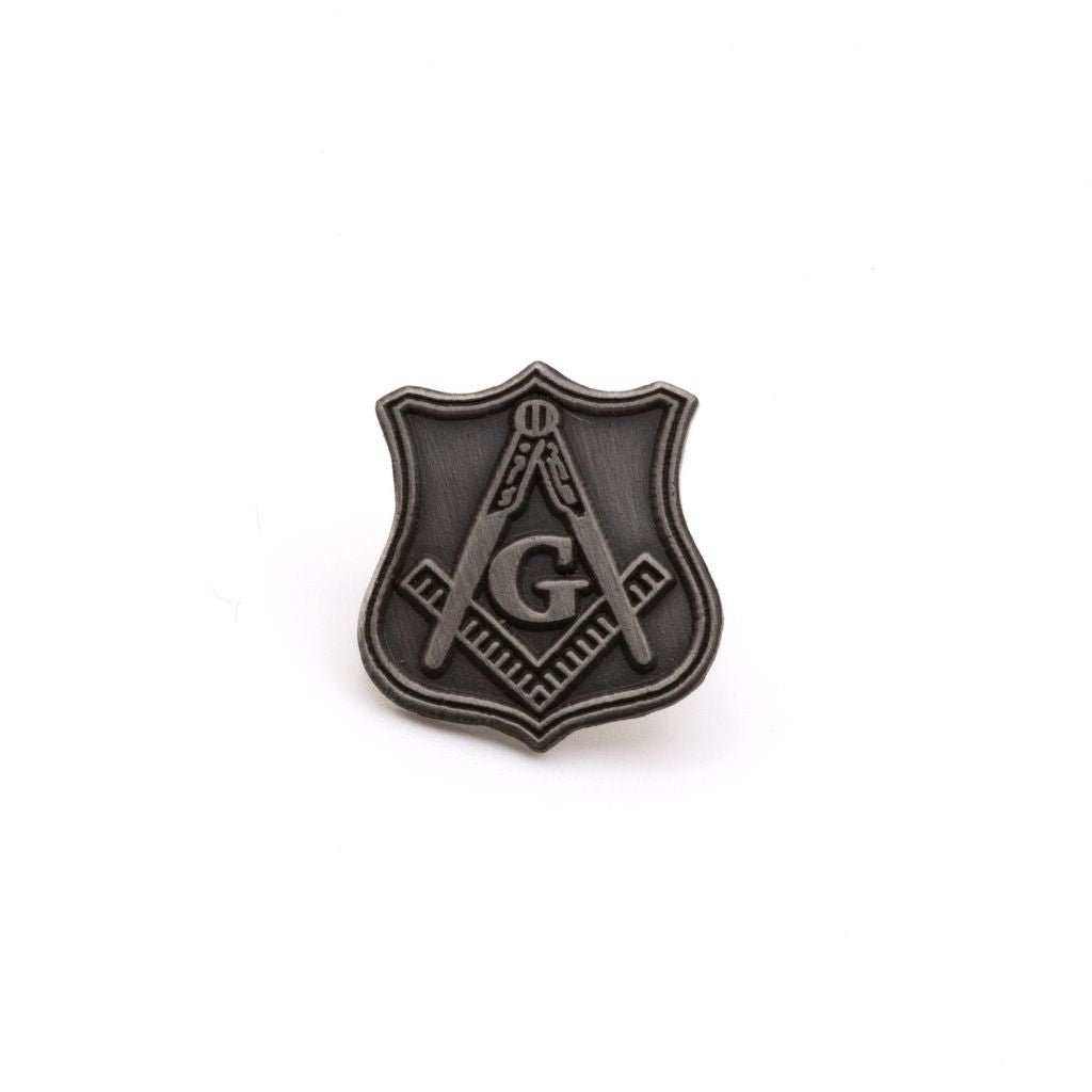 Silver Square and compass on a shield shaped lapel pin on a white background