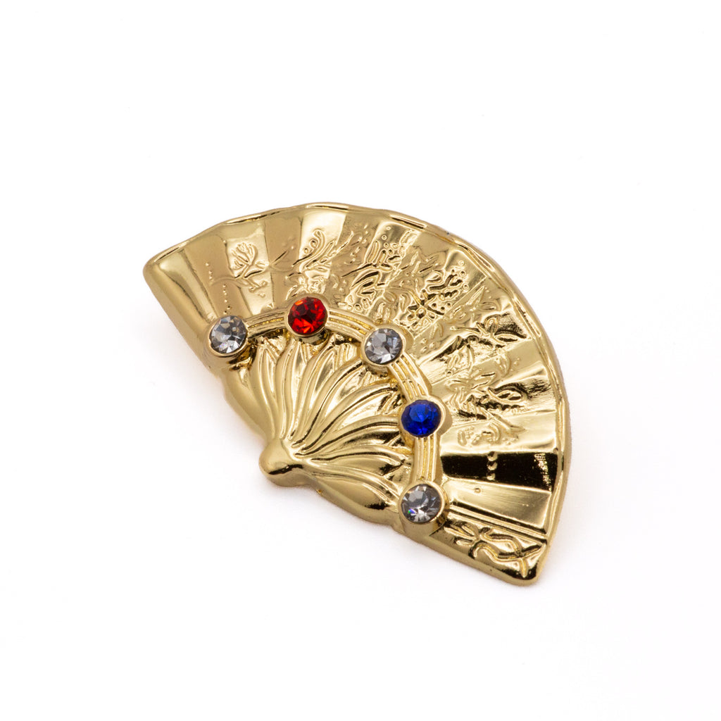 Gold fan-shaped brooch with imitation gemstones on a white background