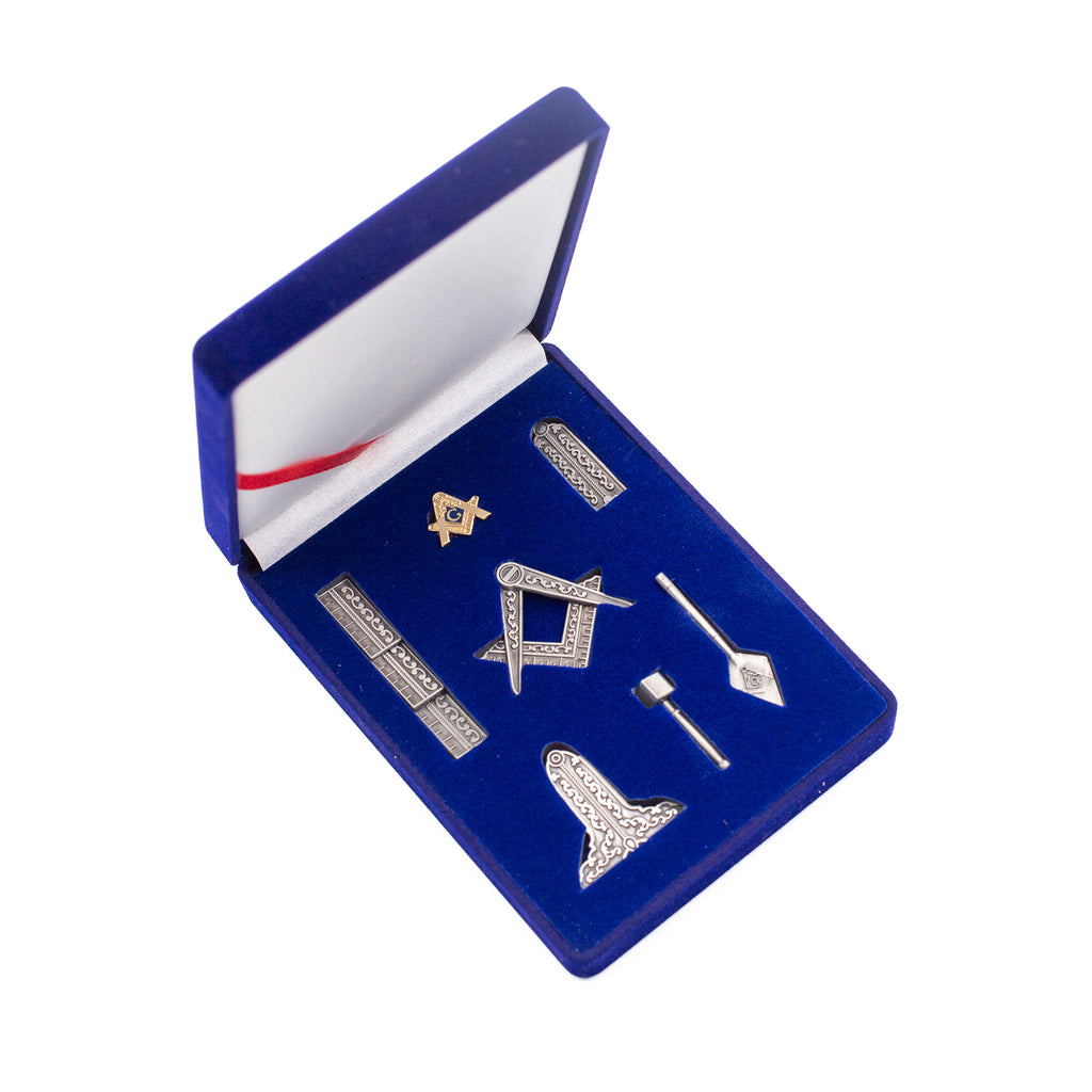 Set of mini silver Masonic tools in a blue box with a red ribbon on a white background.
